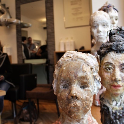 Kunst erobert in Sülz und Klettenberg wieder die Geschätfsläden – so wie hier die Wachsfiguren in „Die Haarschneider“.