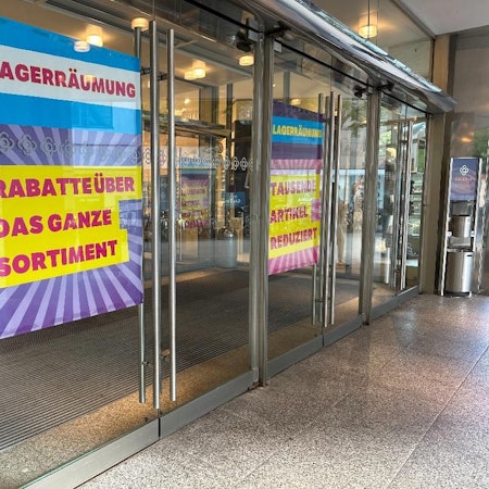 Große Plakate in einem Schaufenster weisen auf eine Lagerräumung hin.