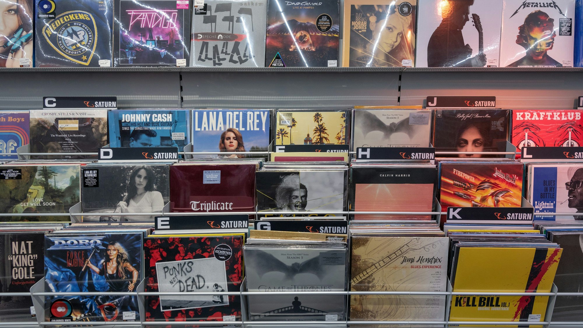 Schallplatten stehen gestapelt hintereinander in einem Regal.