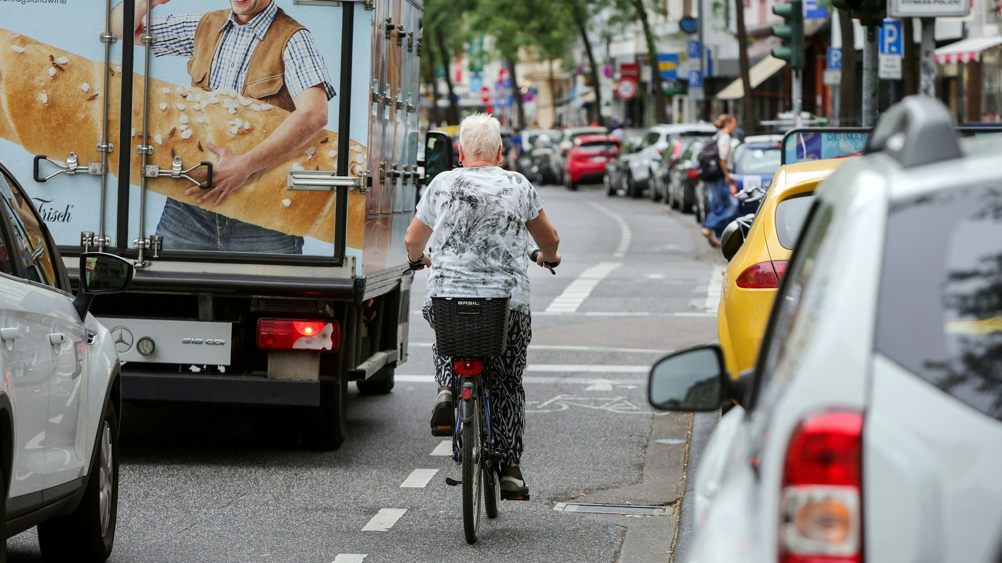 An der Neusser Straße in Nippes herrscht dichter Verkehr. Autos parken dicht an dicht am Straßenrand.