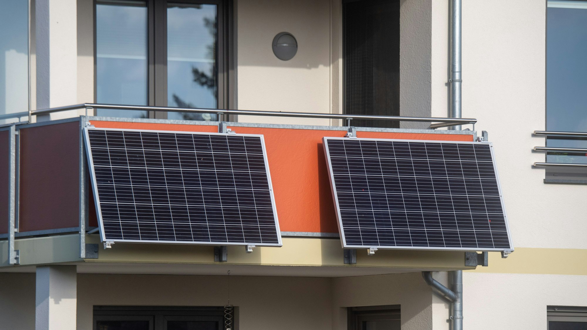 Solarmodule für ein sogenanntes Balkonkraftwerk hängen an einem Balkon.