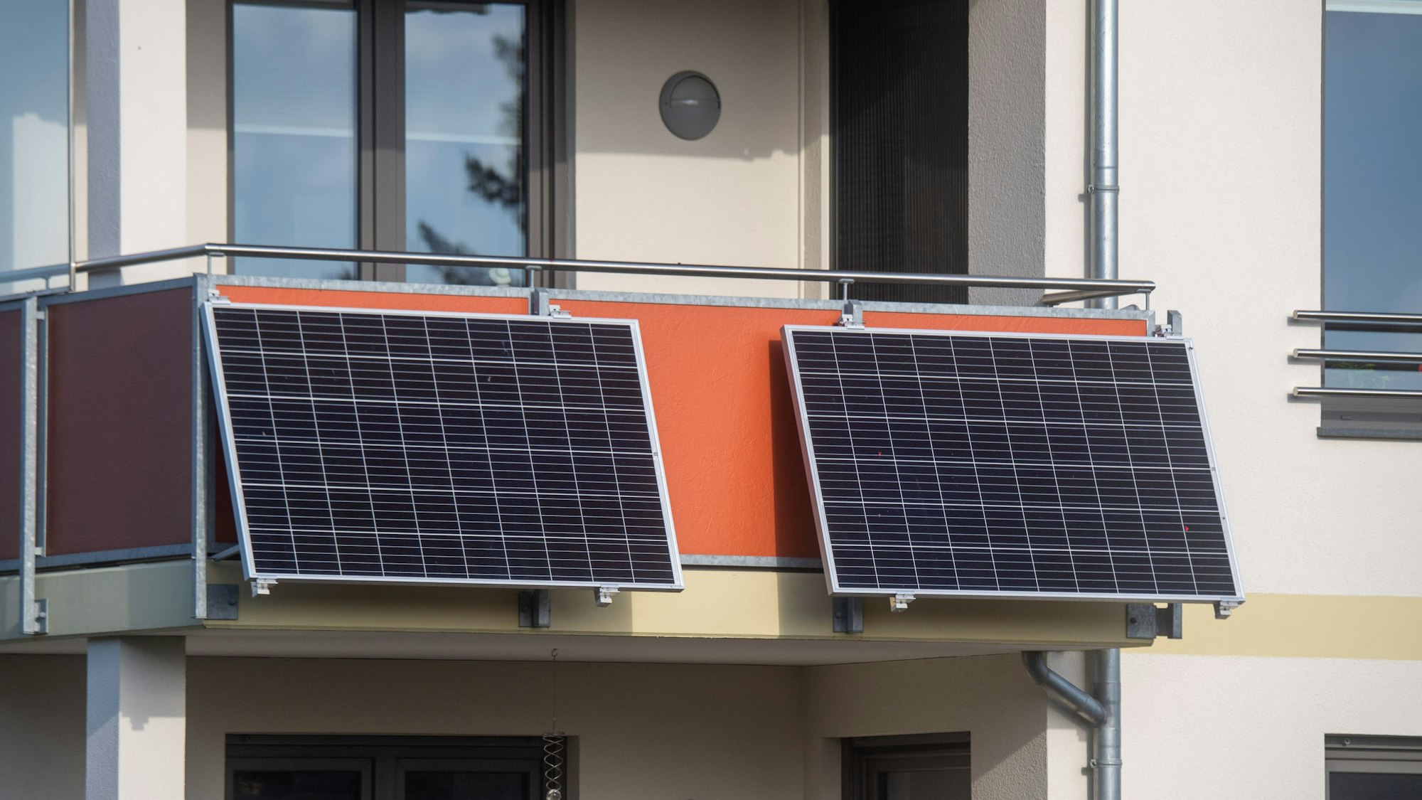 Solarmodule für ein sogenanntes Balkonkraftwerk hängen an einem Balkon.