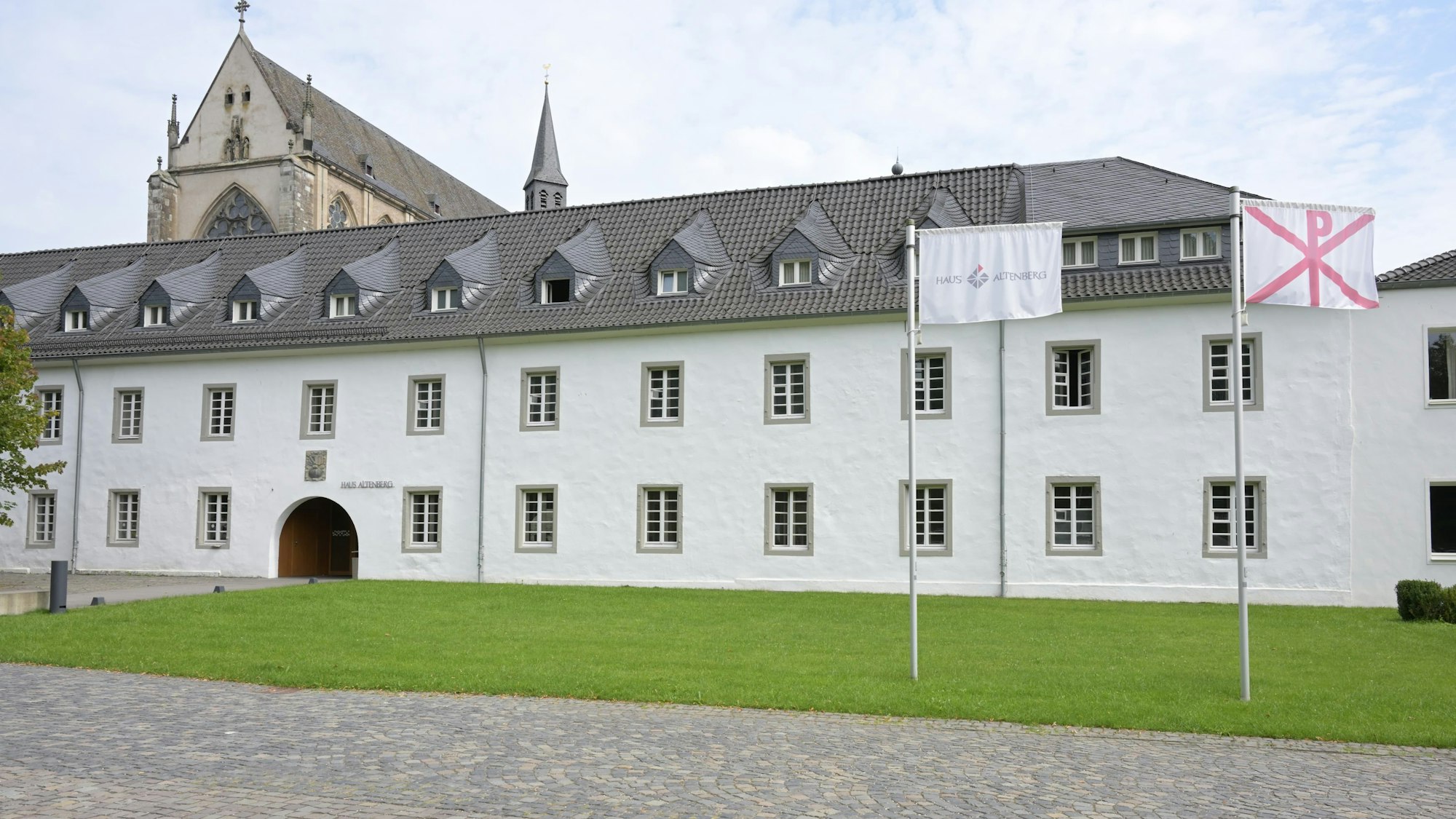 Die katholische Jugendbildungsstätte Haus Altenberg, davor zwei Fahnen.