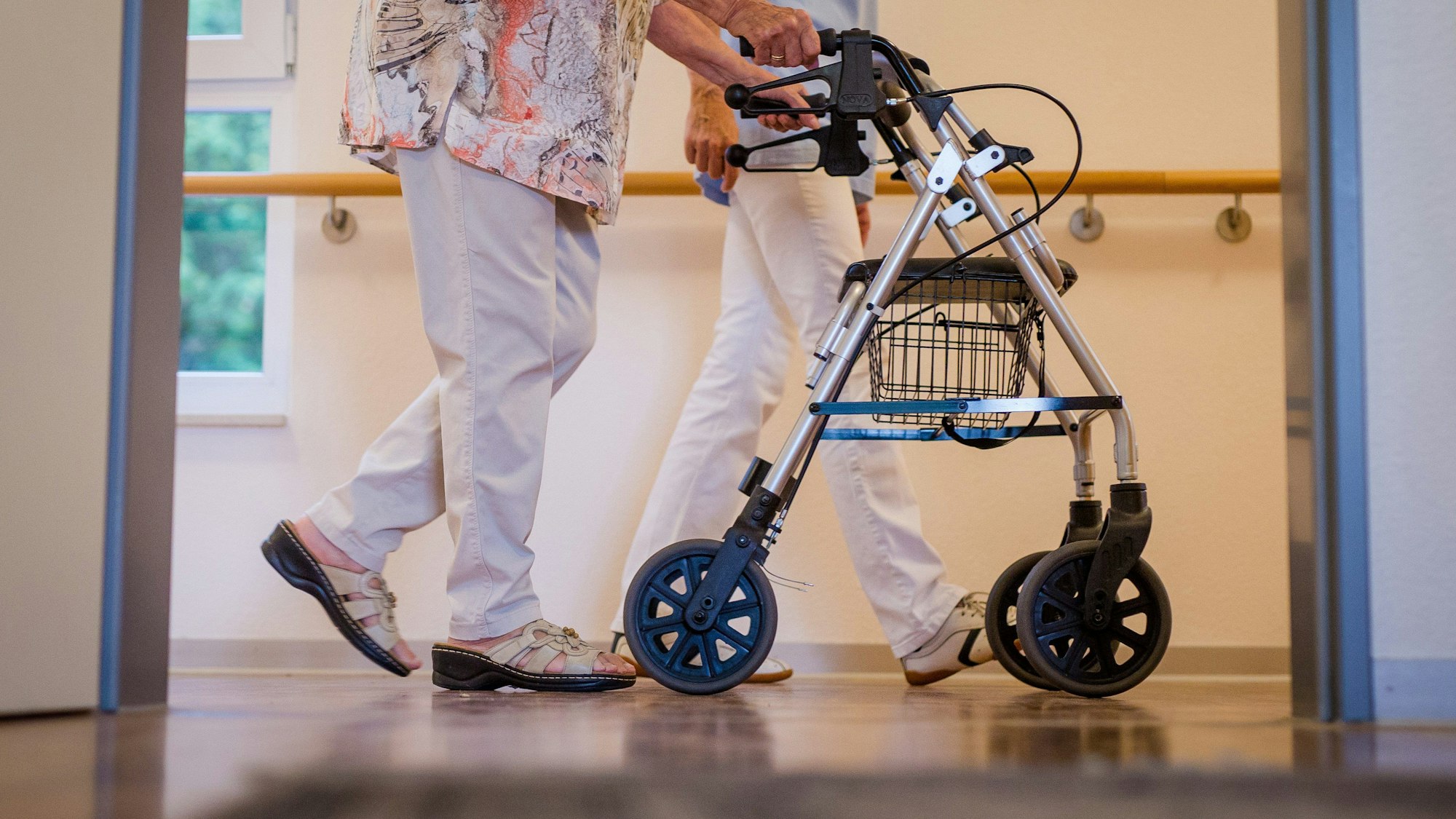 ARCHIV - 23.08.2018, Baden-Württemberg, Stuttgart: Eine Pflegekraft geht in einem Pflegeheim mit einer älteren Dame über einen Korridor. (zu dpa: «Teufelskreis - Wie Personalmangel Seniorenheimen die Luft abschnürt») Foto: Christoph Schmidt/dpa +++ dpa-Bildfunk +++