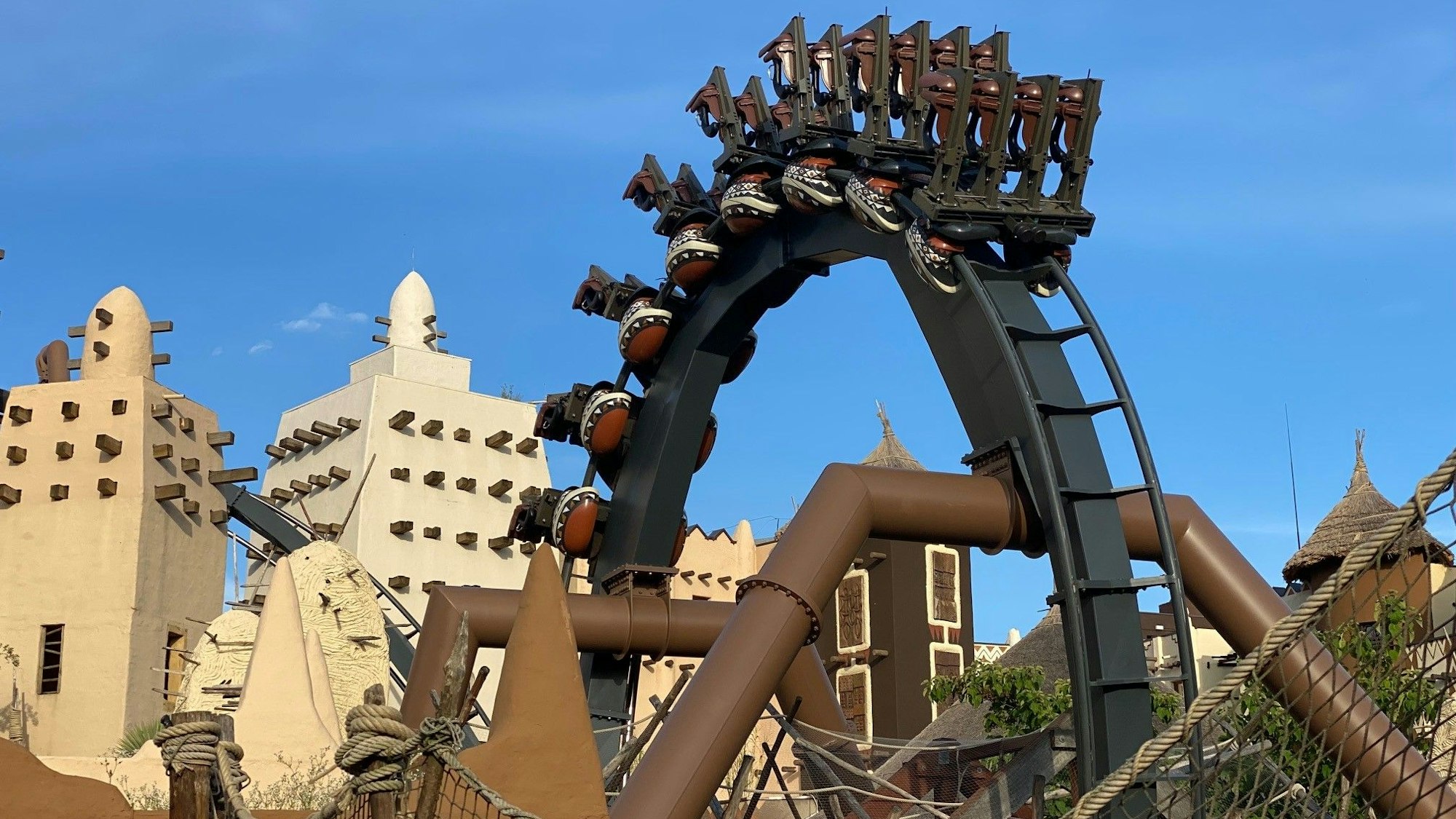 Die Achterbahn Black Mamba im Phantasialand fährt durch einen Looping. Im Hintergrund sieht man die Themenwelt „Deep in Africa“.