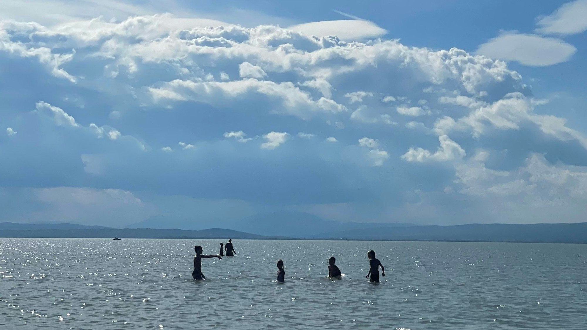 Kinder stehen im seichten Wasser des Neusiedler Sees. Kilometerweit vom Ufer entfernt, kann man im Neusiedler See in Österreich noch stehen. Das Flachwasser an der ungarischen Grenze ist seit 30 Jahren Nationalpark - und hat ein strukturelles Problem.