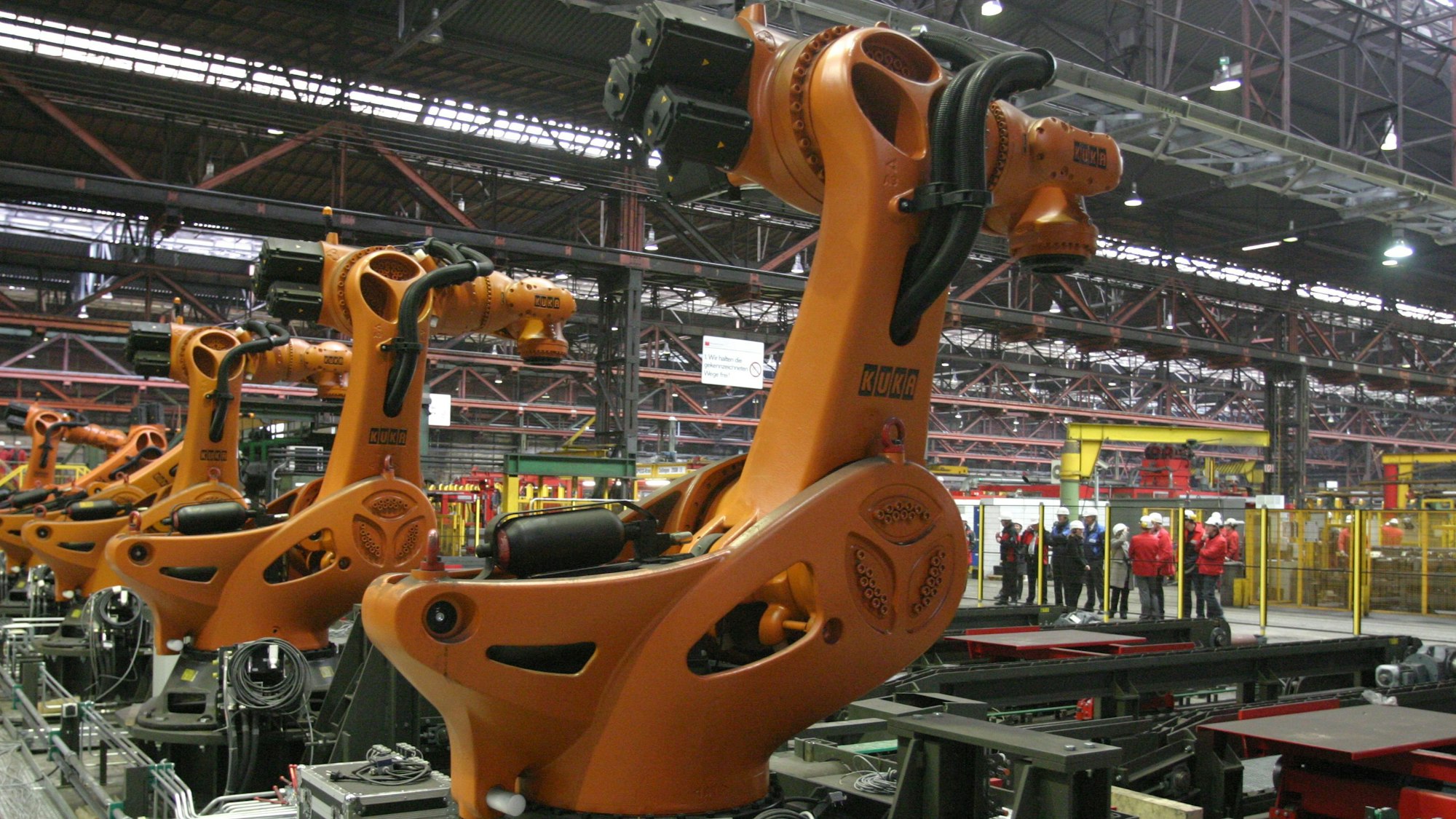 Fünf orangerote Roboter in einer Fabrikhalle von Mannstaedt