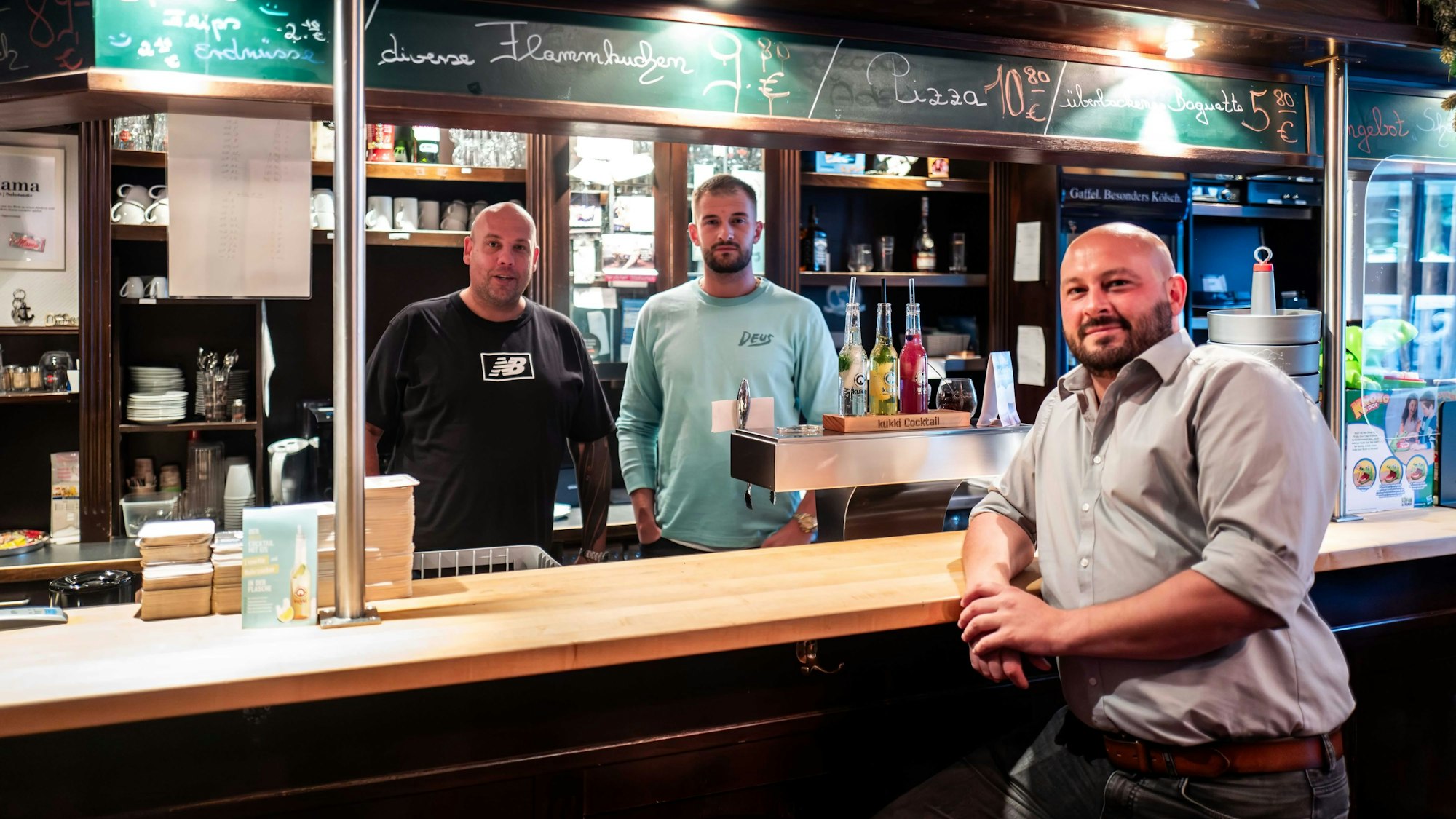 Das Bild zeigt Jörg Peter (l.) und Nico Falkenberg hinter dem Tresen. Verpächter Marius Ruhroth steht davor.