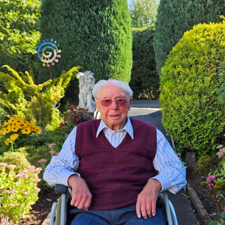 Emil Feyen sitzt in seinem Rollstuhl im Garten.