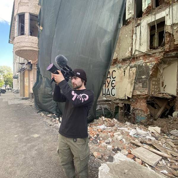 Das Foto zeigt den Filmemacher vor zerstörten Gebäude in der Ukraine.