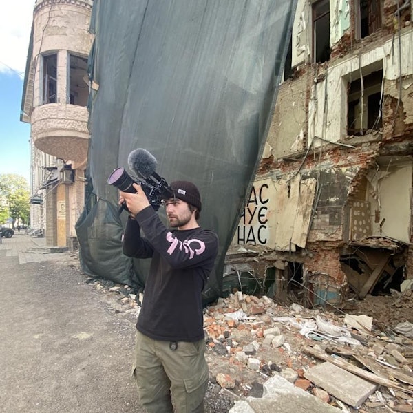 Das Foto zeigt den Filmemacher vor zerstörten Gebäude in der Ukraine.
