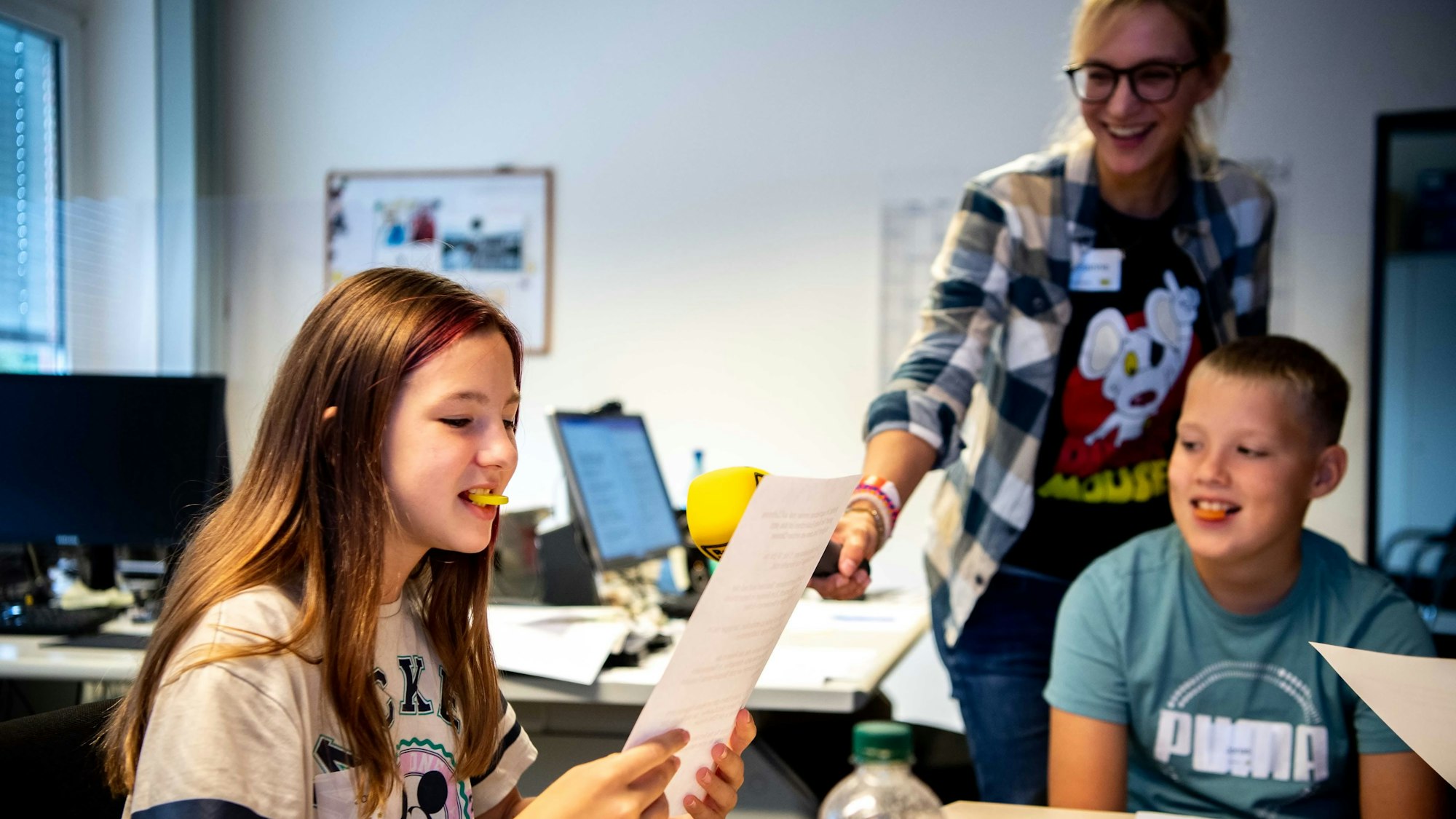 Das Bild zeigt Schülerin Josie, die mit einem gelben Gummitaler im Mund versucht, die Nachrichten aufzusagen.