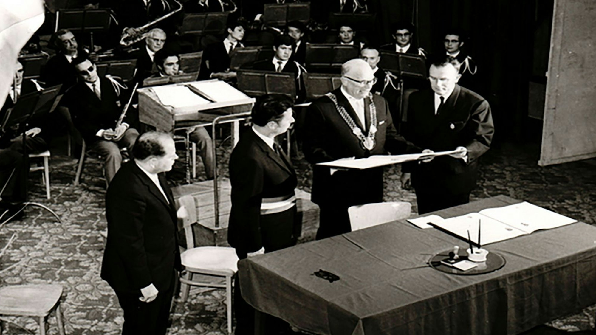 Eine alte Schwarz-Weiß-Aufnahme zeigt die Unterzeichnung der Partnerschaftsurkunde.