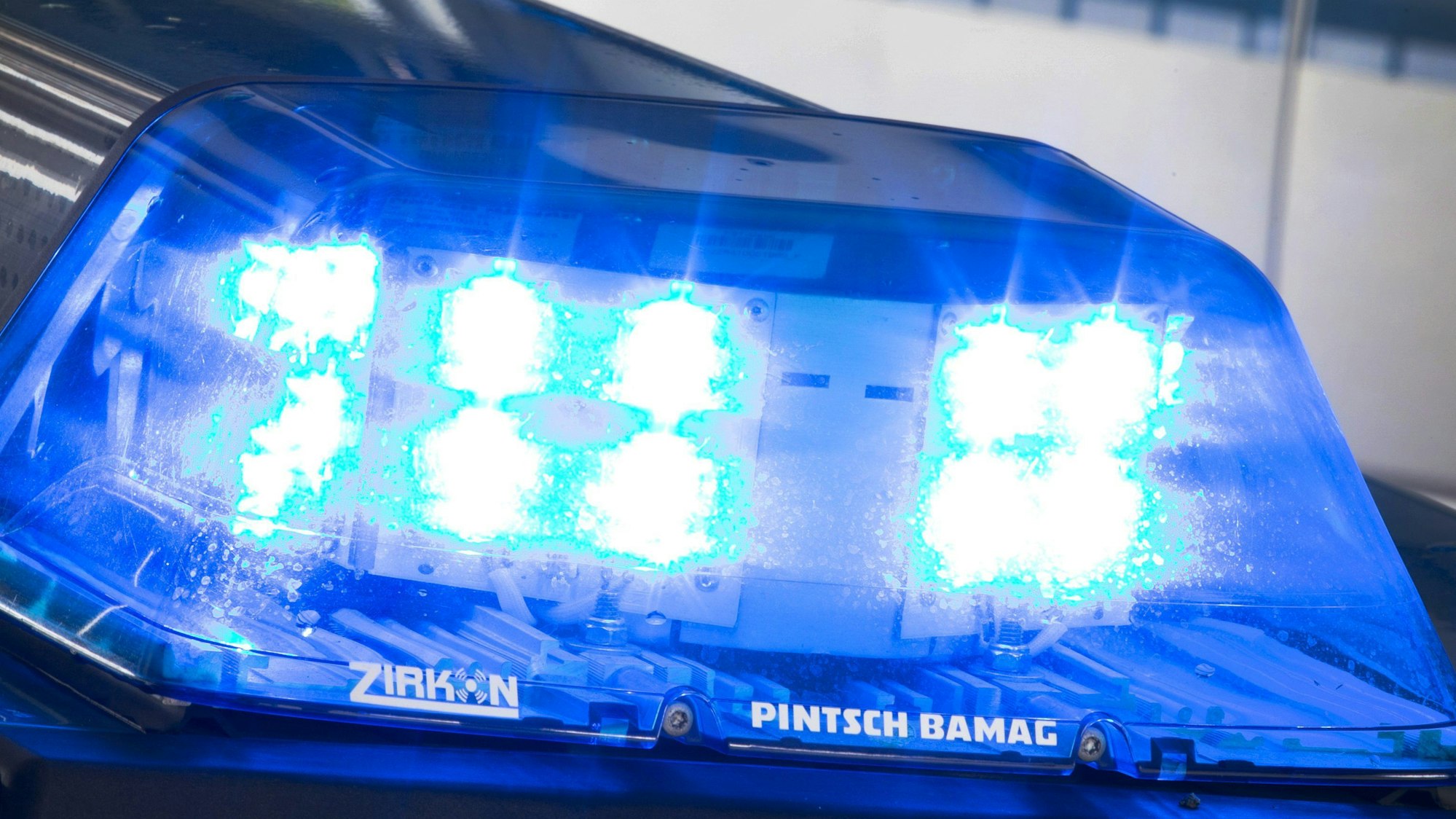 Ein Blaulicht leuchtet während eines Einsatzes auf dem Dach eines Polizeiwagens.