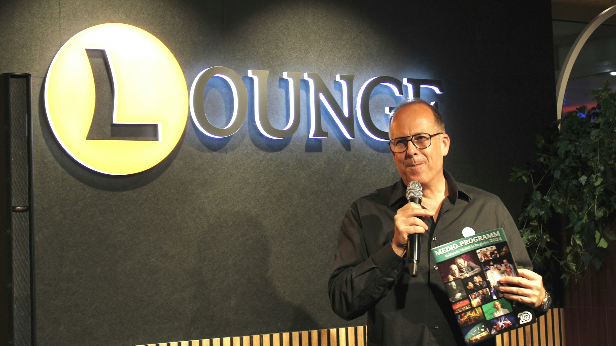 Ein Mann präsentiert ein Programmheft.