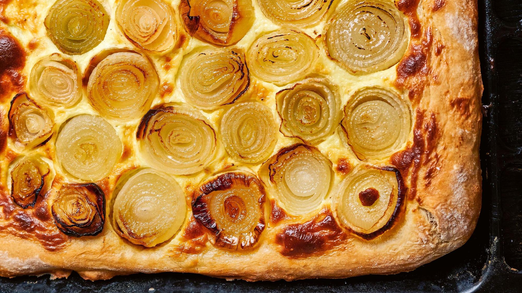 Zwiebelkuchen liegt auf einem Backblech.