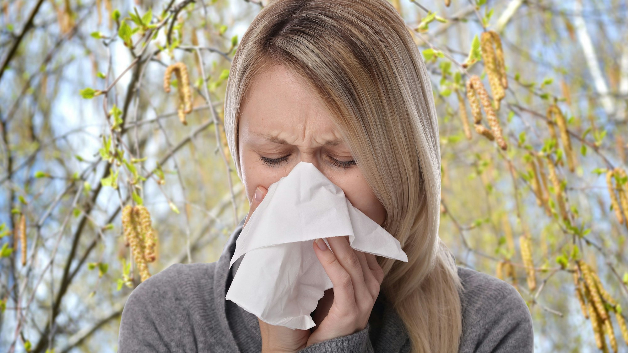 Frau niest in ein Taschentuch.