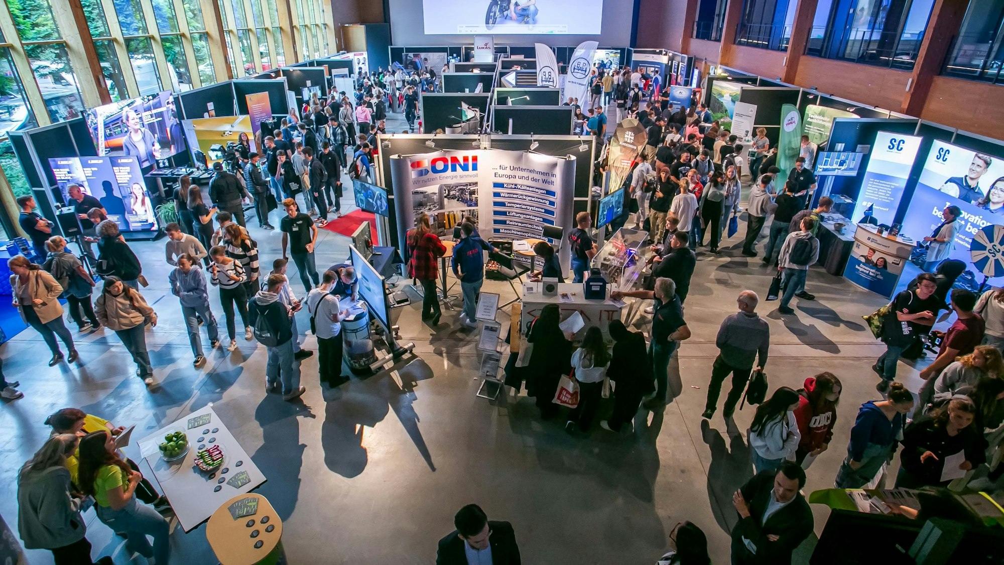 Eine volle Halle mit Ständen von Firmen und vielen jungen Leuten.