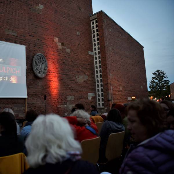 Das Foto zeigt die Leinwand auf dem Quiriniusplatz in Zülpich, davor Zuschauer. Das kostenlose Freiluftkino Zülpich findet immer im Frühjahr und im Herbst auf dem Quiriniusplatz statt.