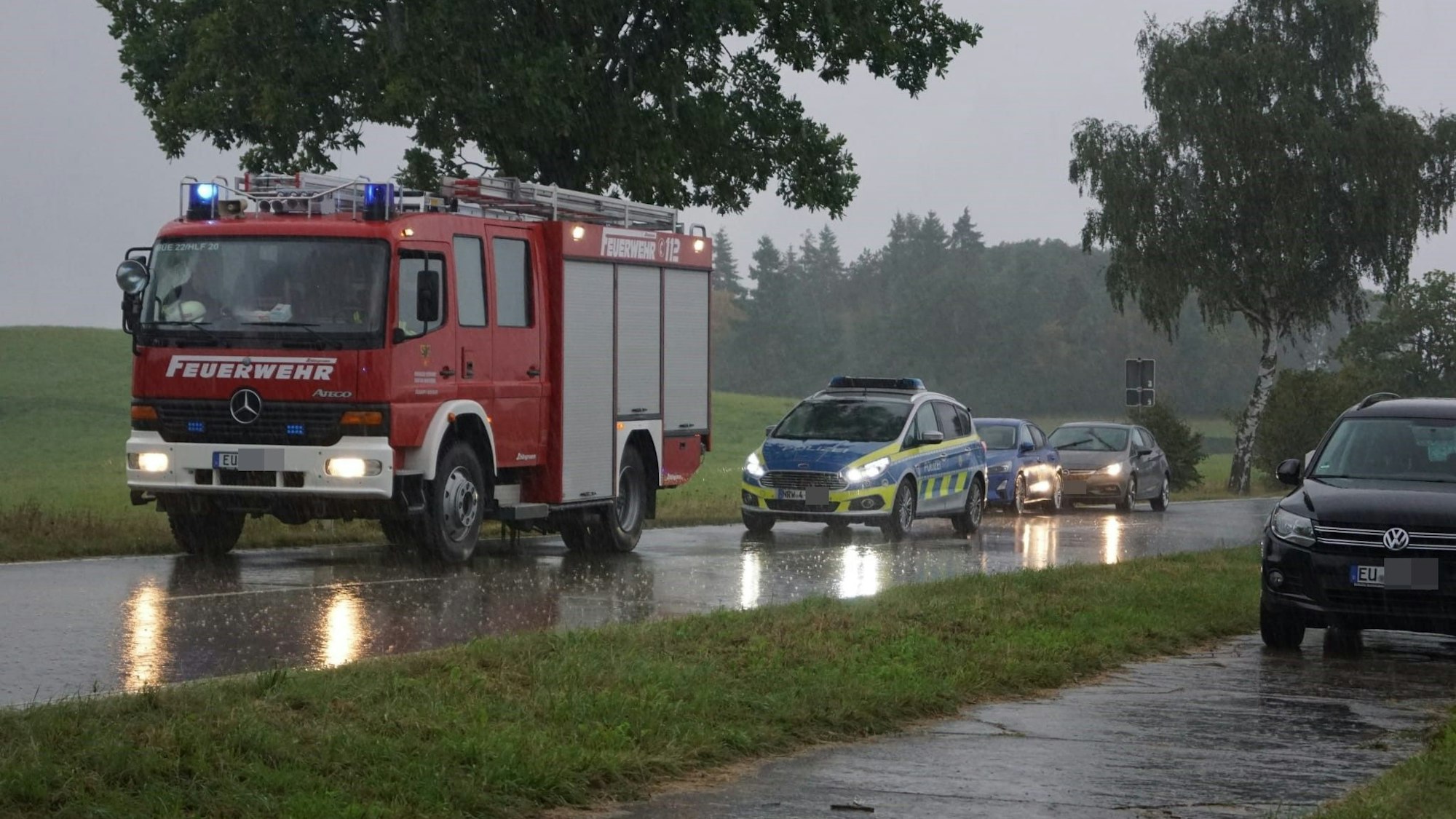 Auf der L234 steht ein Feuerwehrfahrzeug bereit. Ein Polizeiwagen sichert die Unfallstelle.