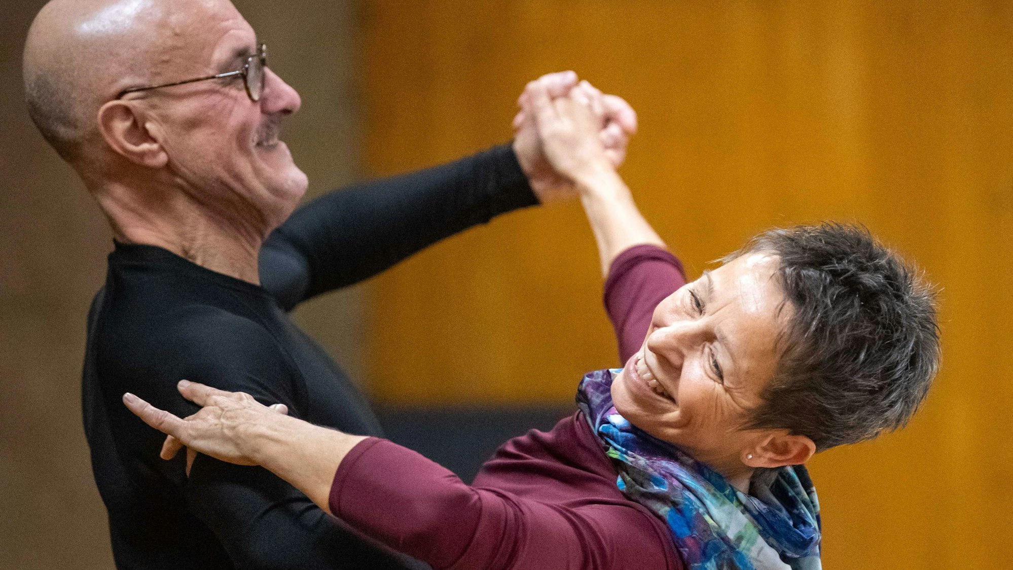 Ein Tanzpaar hält sich in de Armen, beide lachen.