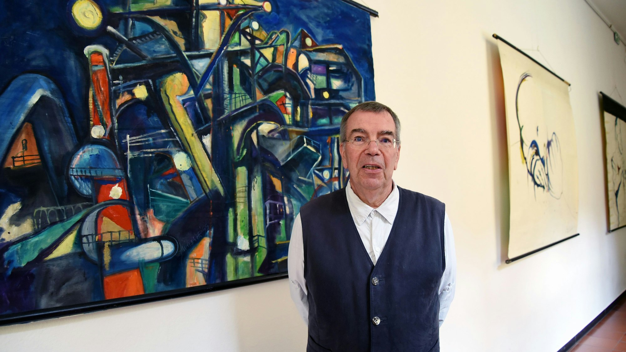 Der Künstler Michael Wittschier steht vor einem seiner Bilder.