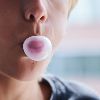 Ein Kind formt mit dem Mund eine Kaugummiblase. (gestellte Szene)