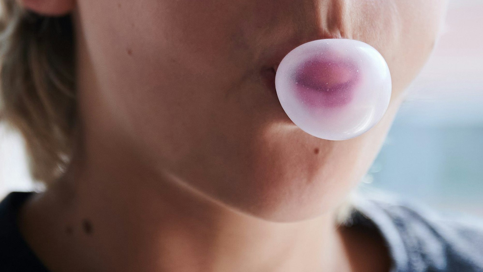 Ein Kind formt mit dem Mund eine Kaugummiblase. (gestellte Szene)