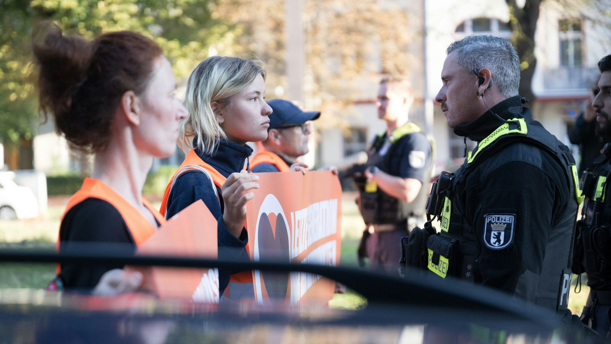 Aktivisten und Aktivistinnen stehen während einer Laufblockade der Klimaschutzgruppe Letzte Generation am 21. September in Berlin vor Polizeibeamten.