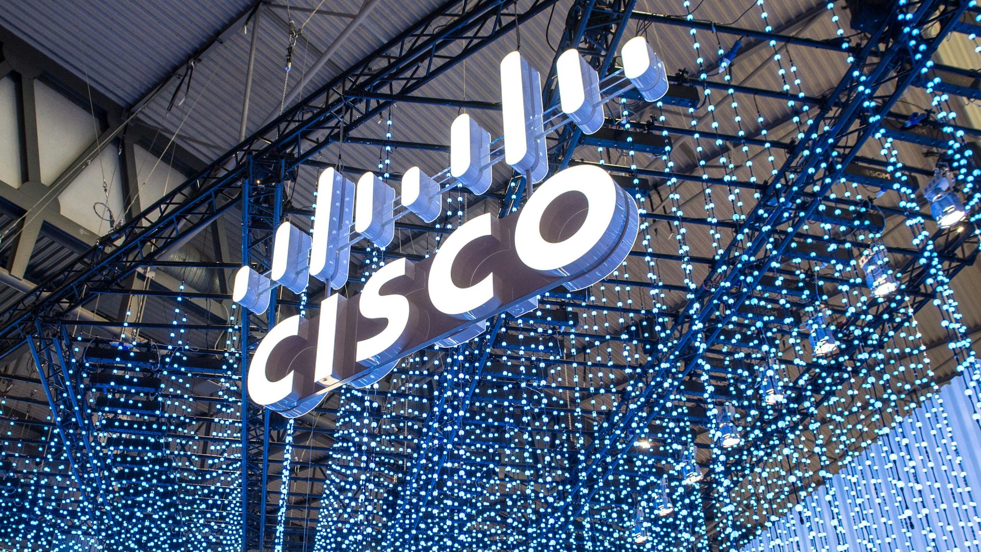Das weiße Cisco-Logo hängt während der Mobilfunk-Messe „Mobile World Congress“ vor verschiedenen Leuchtstäben von der Wand. Der Netzwerk-Spezialist Cisco will per Übernahme zu einem der größten Software-Unternehmen weltweit aufsteigen. (Archivbild)
