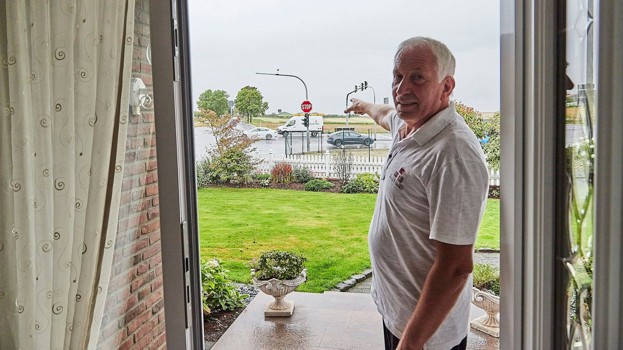 Dieter Hammes weist aus der geöffneten Eingangtür auf die naheliegende Kreuzung.