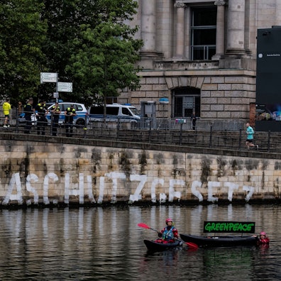 Aktivisten der Umweltschutz-Organisation Greenpeace haben auf der Kaimauer unterhalb des Reichstages das Wort ‚Klimaschutzgesetz‘ geschrieben.