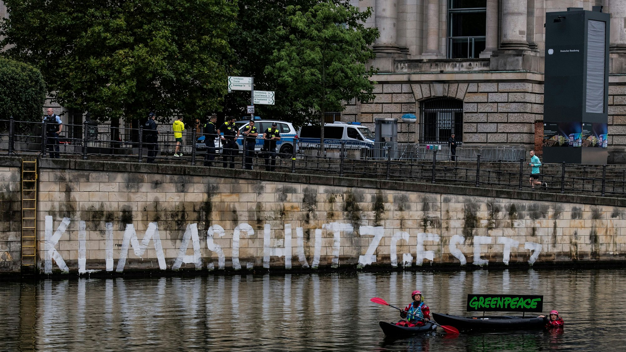 Aktivisten der Umweltschutz-Organisation Greenpeace haben auf der Kaimauer unterhalb des Reichstages das Wort ‚Klimaschutzgesetz‘ geschrieben.