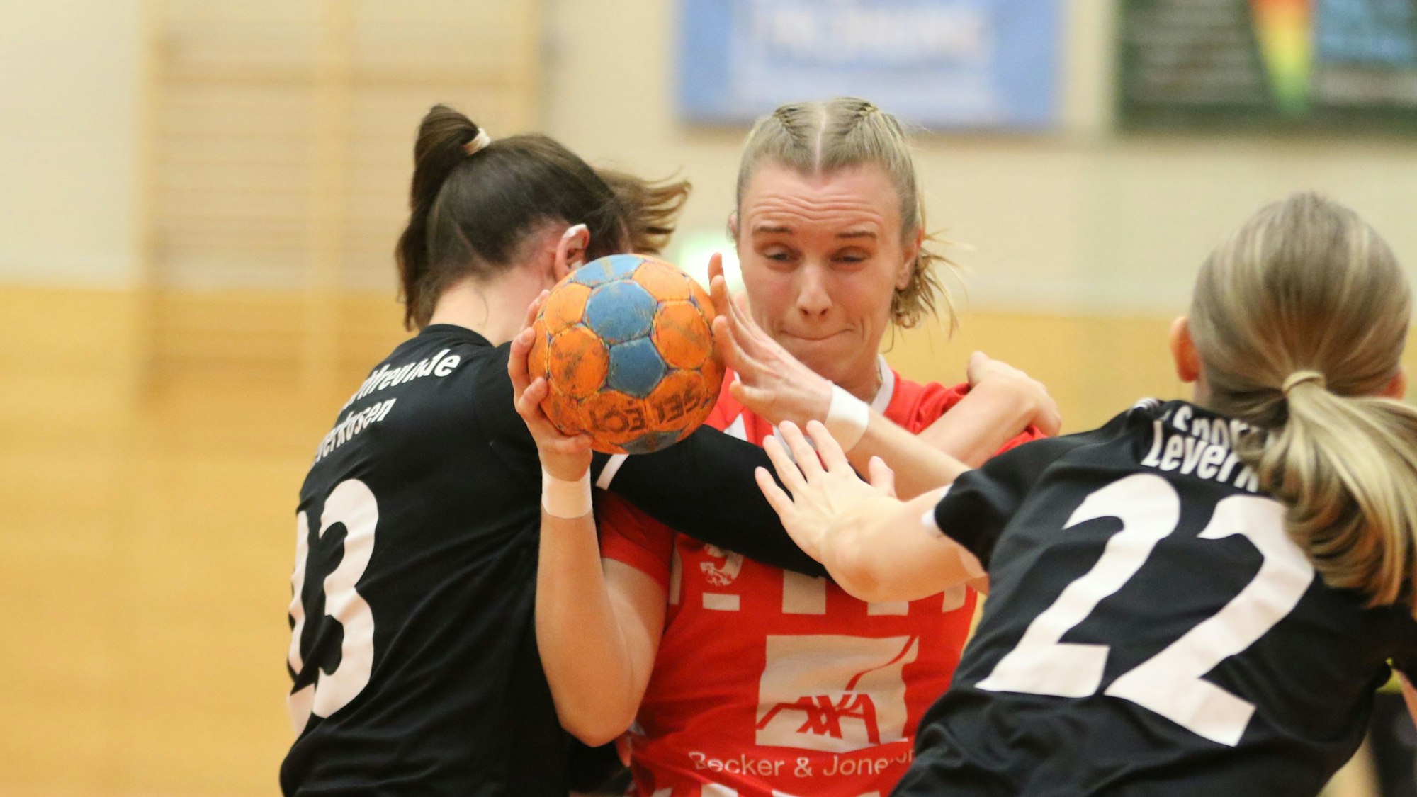 Eine Handballerin wird von zwei Gegenspielerinnen festgehalten.