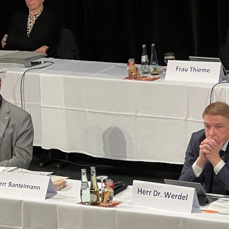 Rhein-Bergs Landrat Stephan Santelmann und Kreisdirektor Dr. Erik Werdel sitzen an einem Tisch auf einem Podium bei einer Kreistagssitzung.