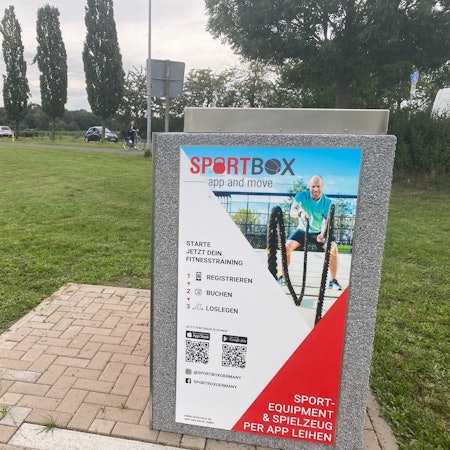 Zu sehen ist die mit Bedienungsinformationen beschriftete Sportbox auf der Freizeitwiese.