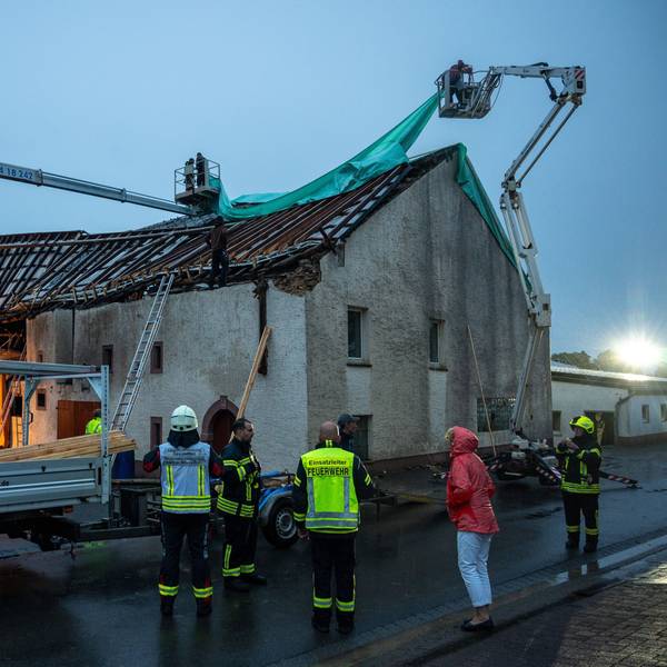 Feuerwehr und Einsatzkräfte kämpfen mit Schäden an einem abgedeckten Häuserdach im rheinland-pfälzischen Nusbaum, die durch einen Tornado verursacht wurden.