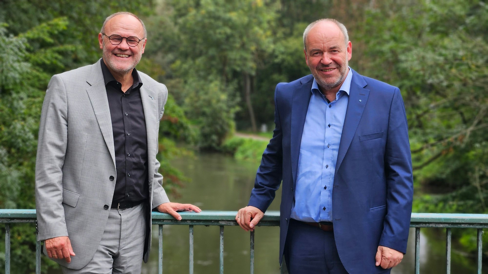Zwei Männer stehen auf einer Brücke über einem Fluss.