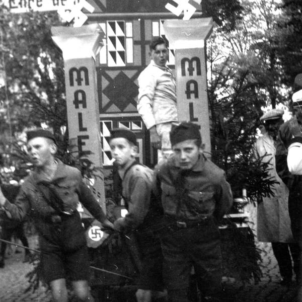 Drei Jungen in Uniformen der Hitlerjugend ziehen einen Wagen.