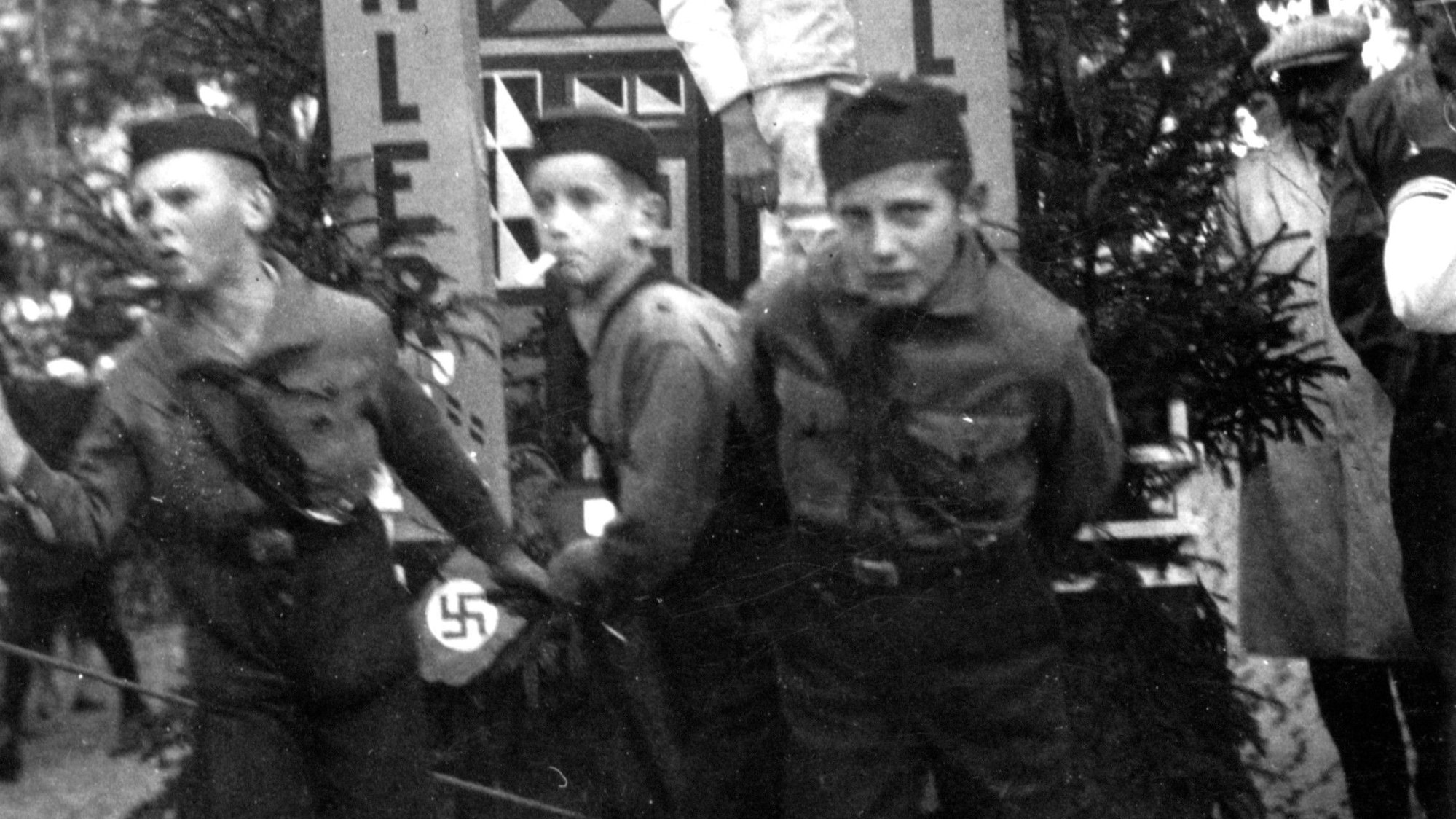 Drei Jungen in Uniformen der Hitlerjugend ziehen einen Wagen.