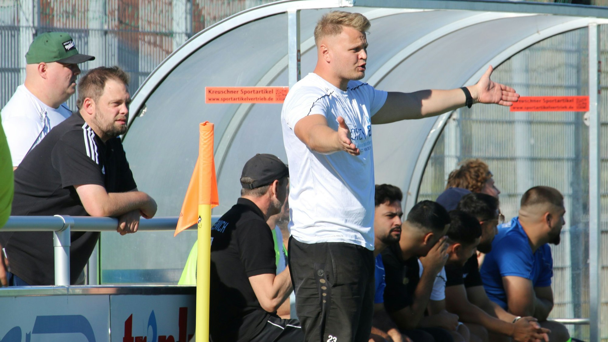 Ein Fußballtrainer breitet die Arme aus.