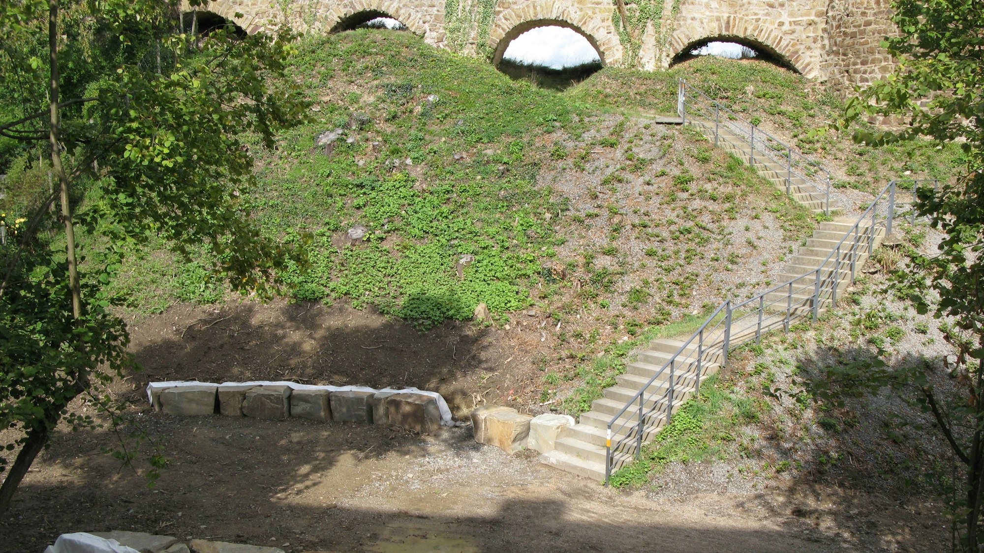 In einem Hang unterhalb der alten Stadtmauer sind eine Treppe gebaut und Bruchsteinquader gesetzt worden.