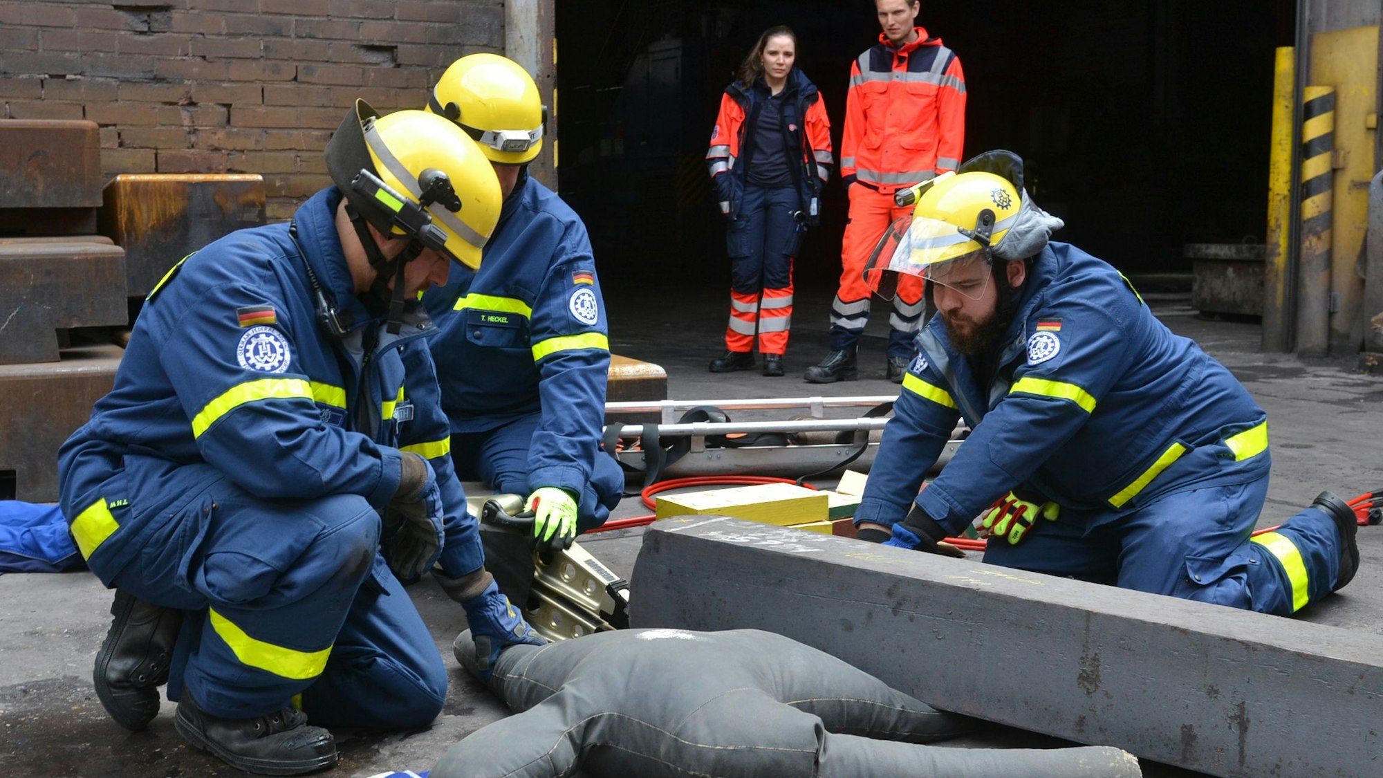 Das Bild zeigt drei THWler, wie sie mit schwerem Gerät eine Puppe unter einem Stahlträger befreien.