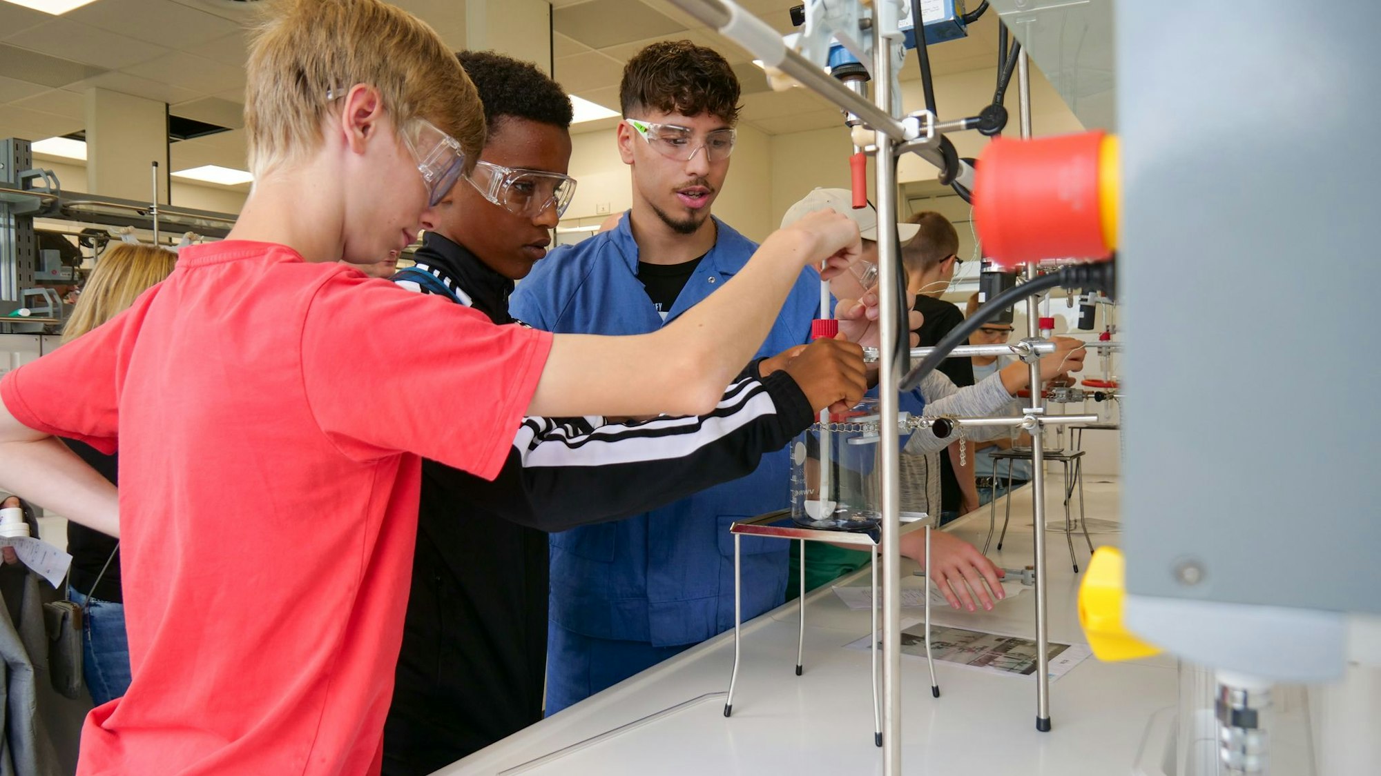 Auf dem Bild sind drei Jungen zu sehen, die in einem Chemielabor ein Experiment durchführen.