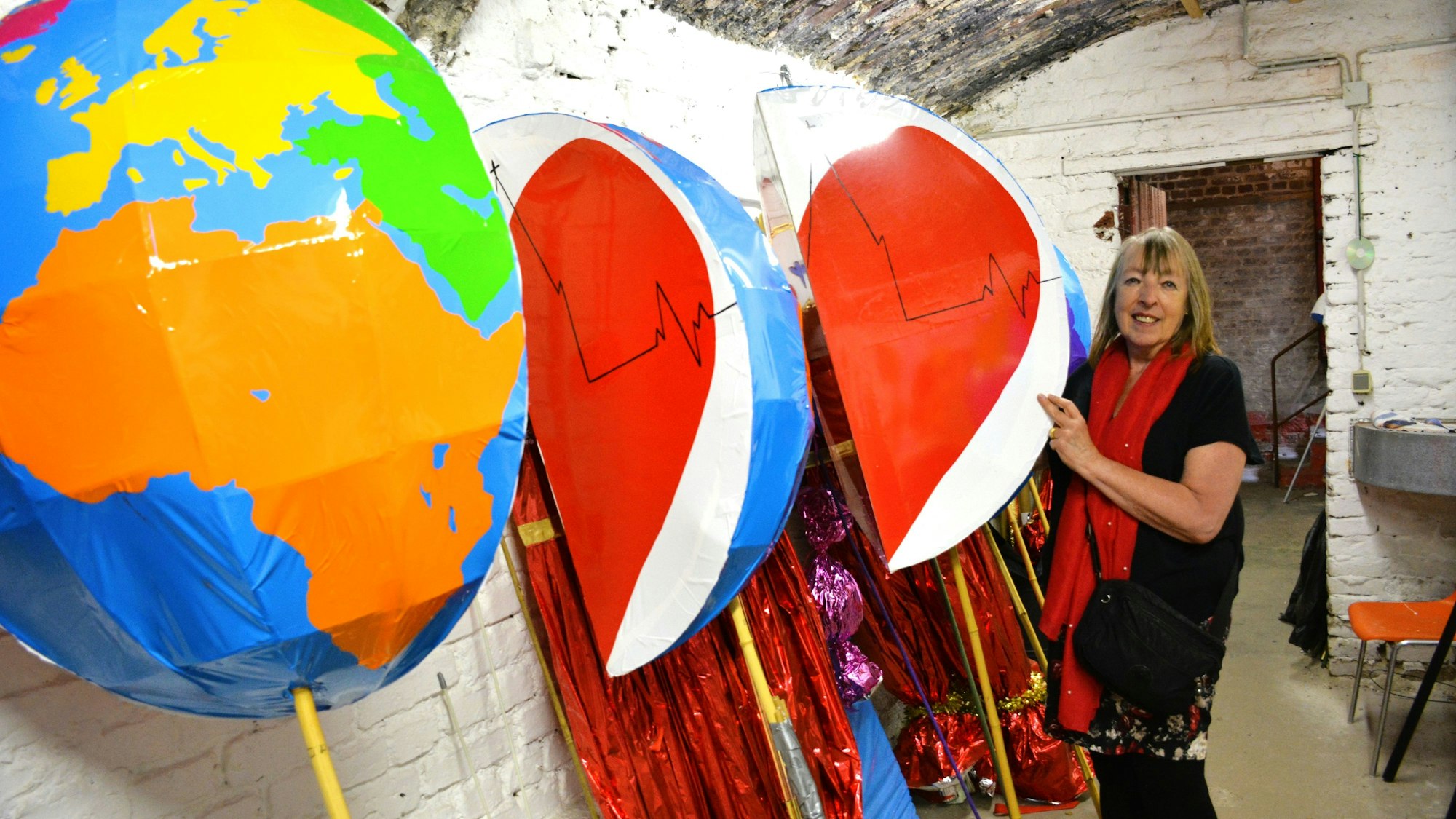 Eine Frau steht neben Tafeln, die man tragen kann und die Weltkugeln symbolisieren.