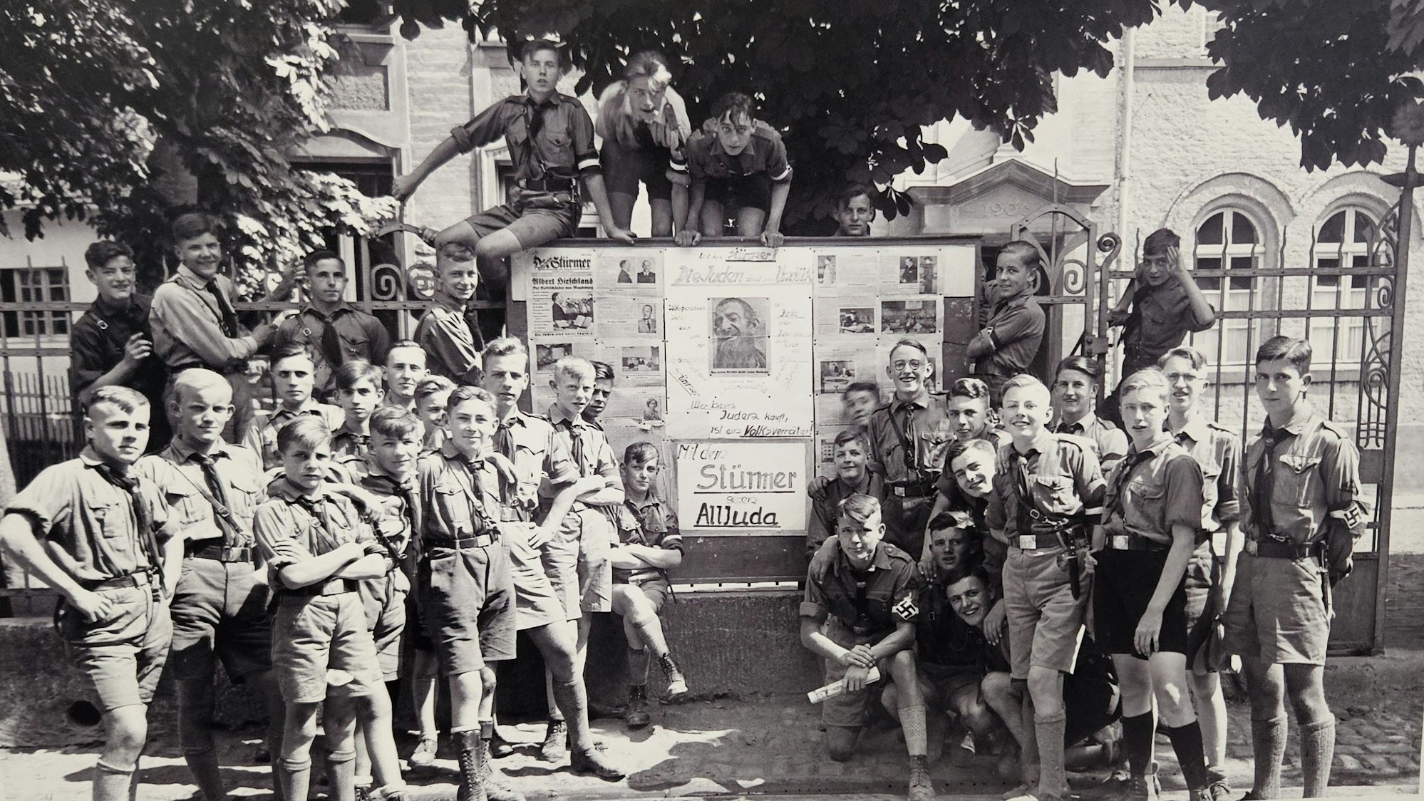 Jungen in HJ-Uniformen stehen vor einem großen Schaukasten.