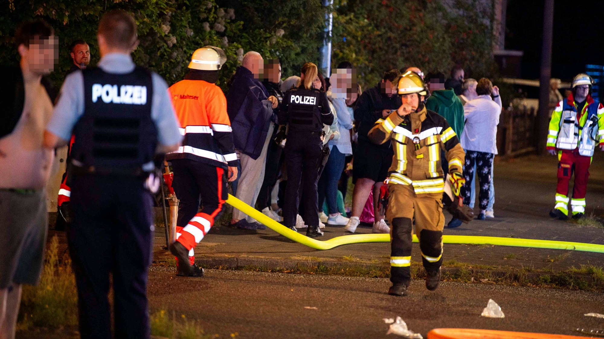 Das Bild zeigt Polizisten und Einsatzkräfte, wie sie sich um die Bewohner kümmern