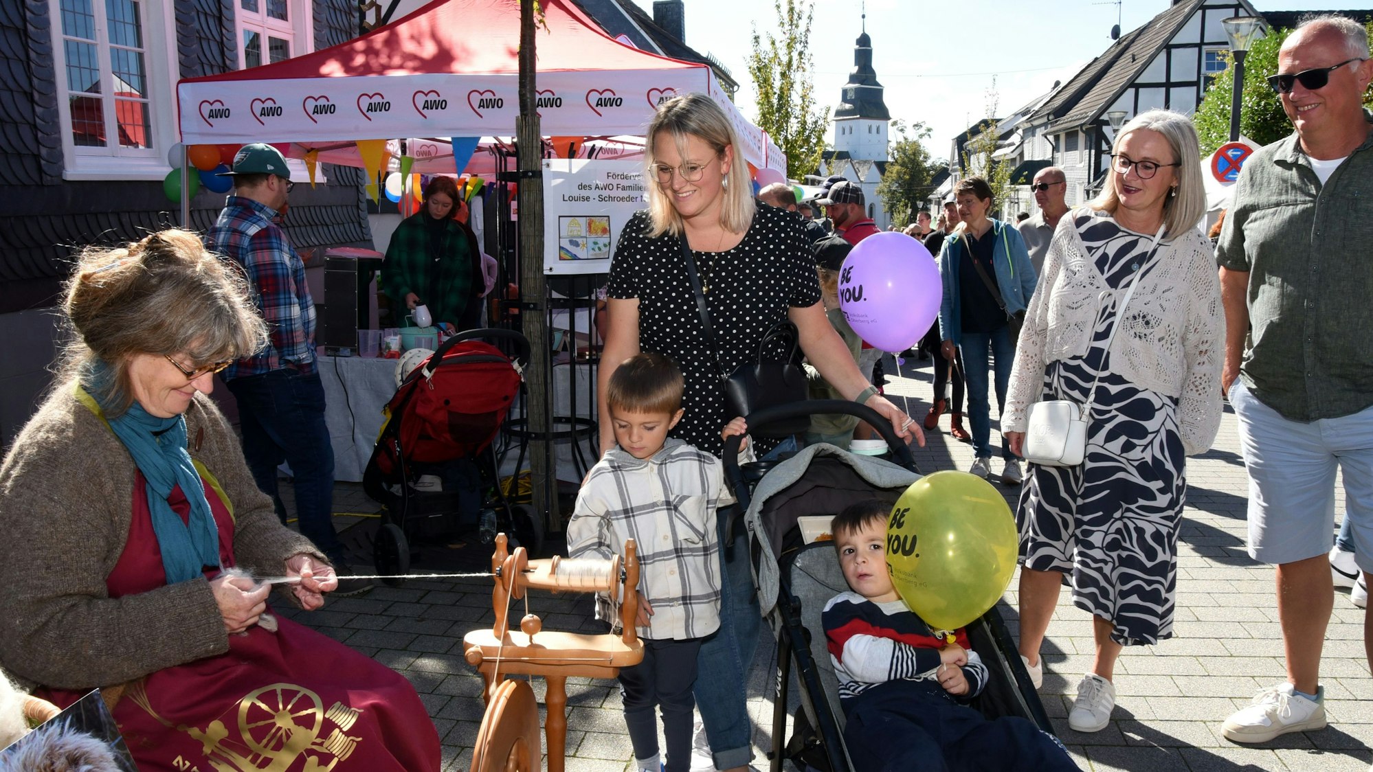 Dicht gedrängt stehen Besucherinnen vor einer Frau, die an einem Spinnrad arbeitet.