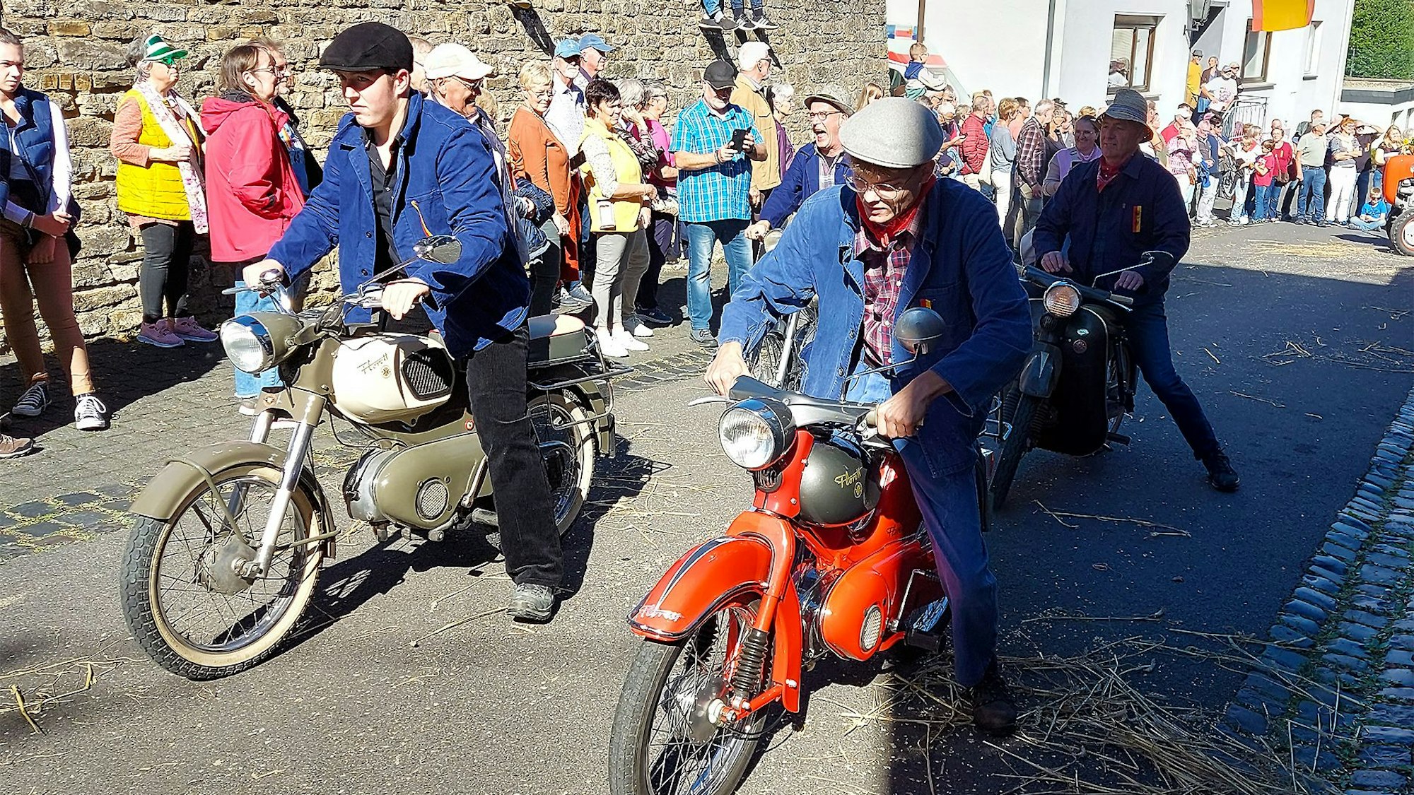 Vier Männer fahren auf alten Motorrädern durch den Ort.