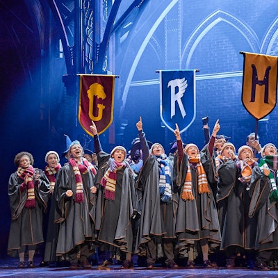 Kinder in Umhängen stehen auf einer Bühne.